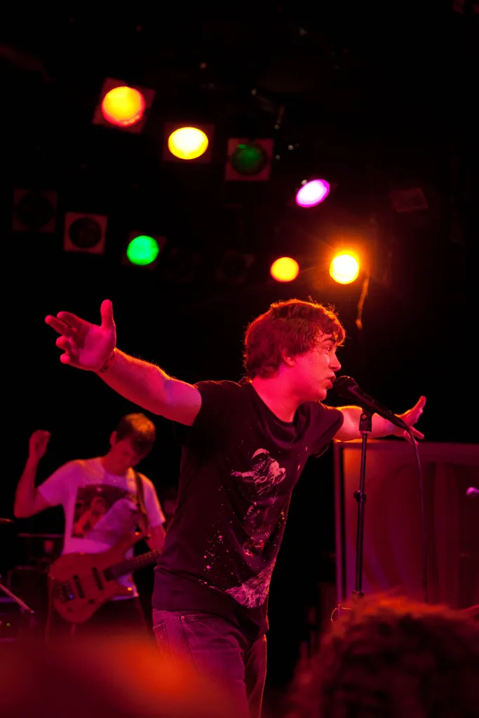 James Bourne on stage with one arm stretched out, a guitarist playing behind him